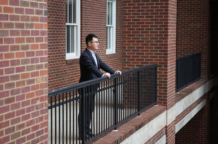 Edward Wang looking over railing into courtyard. 