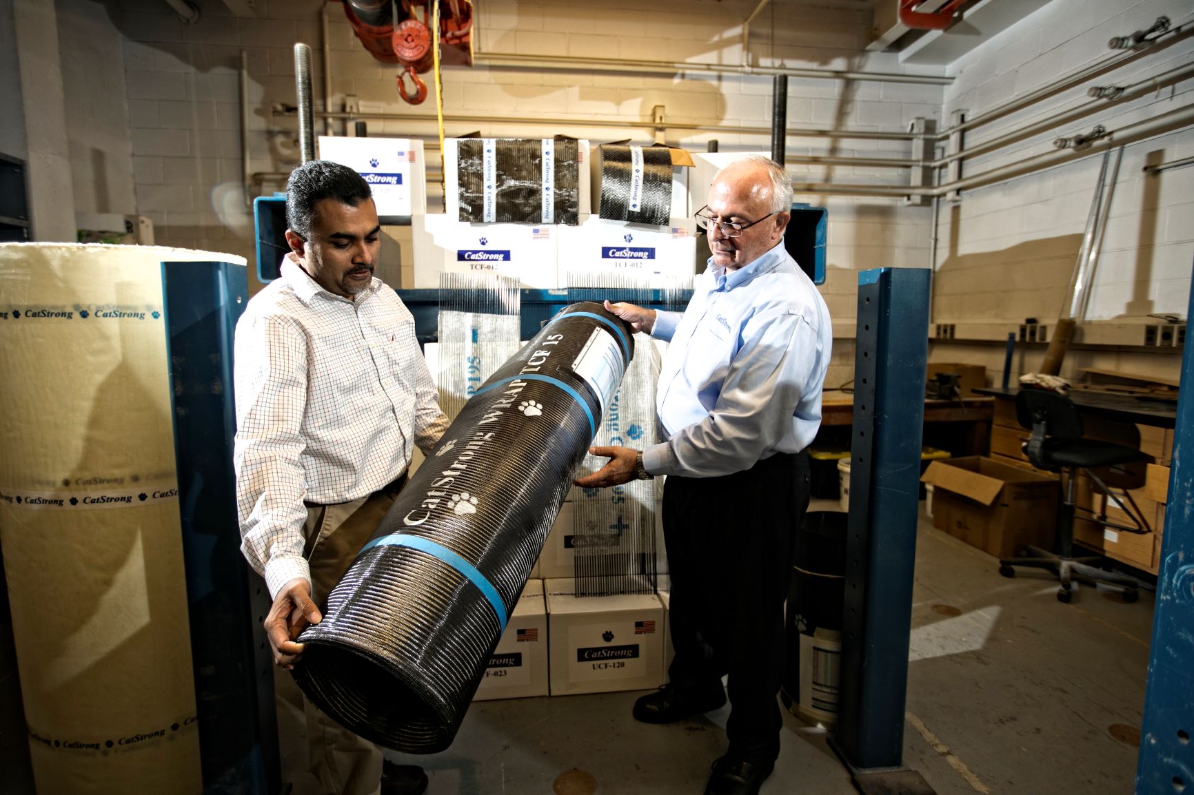 Abheetha Peiris (left) and Issam Harik (right) holding a roll of CatStrong carbon-fiber panels